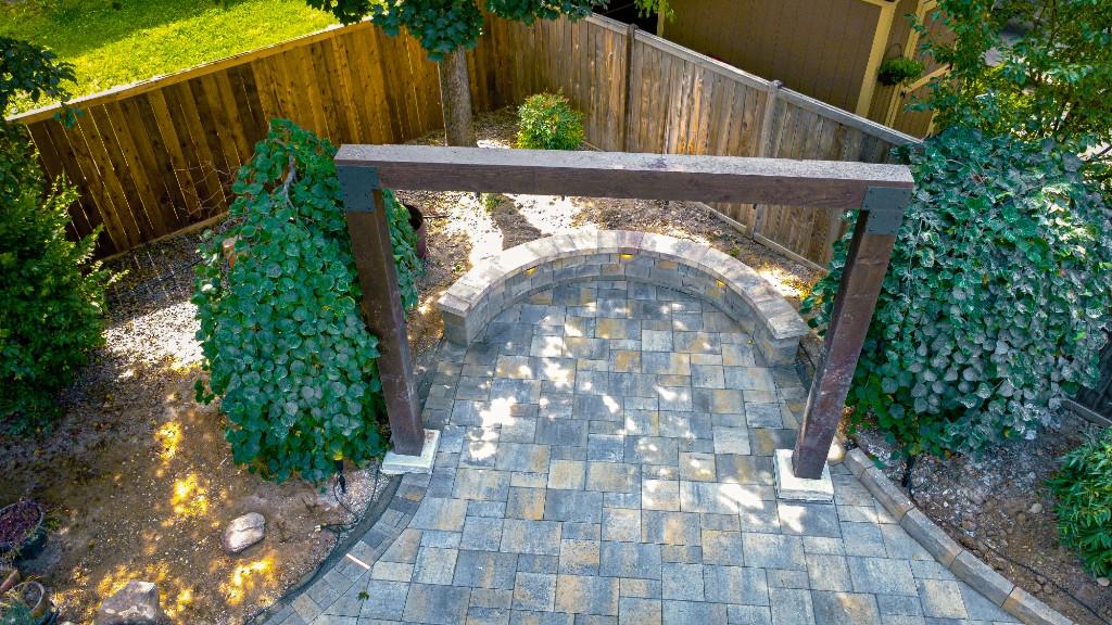 Timber swing arch over a paver patio with a lit curved seat wall